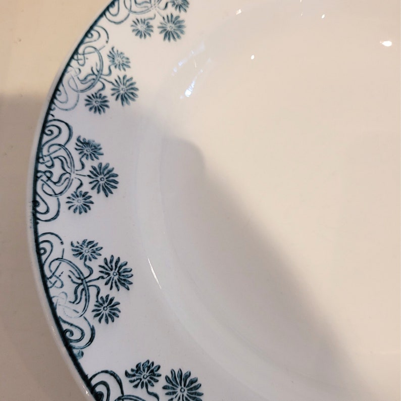 Może przedstawiać: Biała ceramiczna miska z niebiesko-białym wzorem kwiatowym wok&oacute;ł krawędzi.