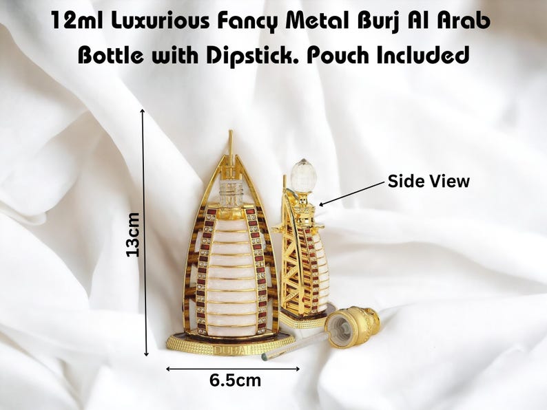 Puede incluir: Una r&eacute;plica de metal dorado del edificio Burj Al Arab en Dubai, un frasco de perfume de 12 ml con un aplicador. El frasco mide 13 cm de alto y 6,5 cm de ancho. El frasco est&aacute; sobre una superficie blanca.