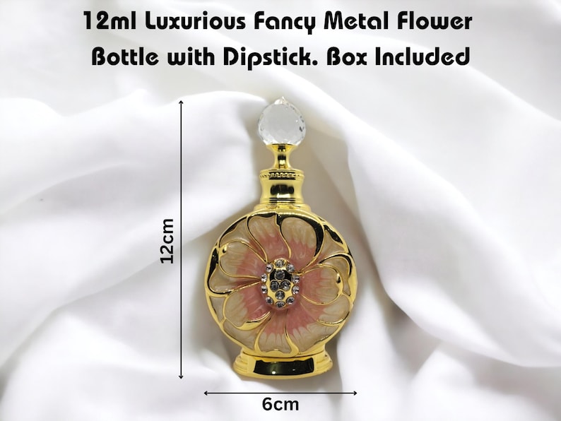 Puede incluir: Una botella de metal dorado con un dise&ntilde;o de flor rosa y blanca. La botella mide 12 cm de alto y 6 cm de ancho. Tiene un tap&oacute;n de vidrio transparente y viene con una caja.