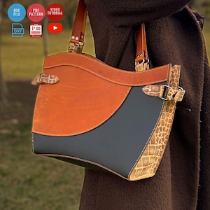 Puede incluir: Bolso tote de cuero hecho a mano con un diseño único. El bolso presenta una combinación de cuero marrón, gris y estampado. Tiene una parte superior curva, correas ajustables y hebillas decorativas. El bolso está diseñado para transportar objetos.