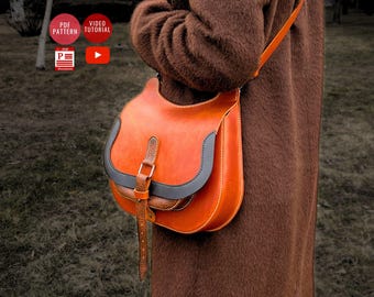 May include: A brown leather satchel bag with a black leather trim and a buckle closure. The bag has a long strap and is worn over the shoulder.
