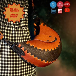May include: A crescent-shaped leather bag featuring a two-tone design with a smooth tan flap and a black embossed body. The bag includes a matching tan leather shoulder strap and is presented with digital icons for a DXF file, PDF pattern, and video tutorial.