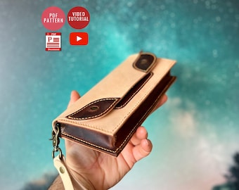 May include: A light brown leather wallet with a dark brown leather trim and a flap closure. The wallet has a strap with a metal clasp. The wallet is being held in a hand.