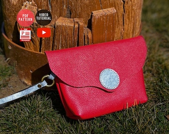 May include: A red leather clutch with a silver circular accent and a strap. The clutch is set against a wooden background and green grass. The image also includes text that says "PDF Pattern" and "Video Tutorial".