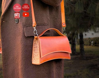 Può includere: Una borsa a tracolla in pelle marrone con chiusura a lembo e manico superiore. La borsa ha un pannello anteriore testurizzato, con effetto coccodrilo, e un pannello posteriore in pelle liscia.