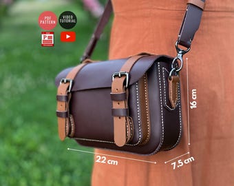 May include: A brown leather crossbody bag with tan leather accents and silver buckles. The bag measures 22 inches wide, 7.5 inches deep, and 16 inches tall.