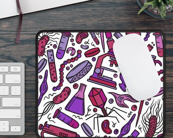 May include: A white mouse pad with a colorful pattern of science-related illustrations. The pattern includes test tubes, beakers, microscopes, and other lab equipment. The mouse pad has a black border.