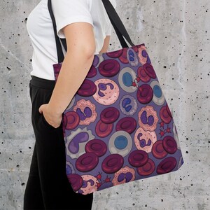 May include: A purple tote bag featuring a colourful pattern of red, pink and blue cells. The bag has a black handle and is made from a durable fabric.