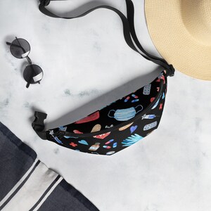 May include: A black fanny pack with a colorful pattern of medical supplies, including face masks, bandages, pills, and gloves. The fanny pack has a black adjustable strap.