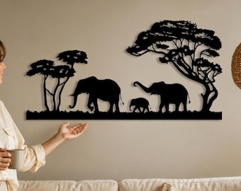 May include: A black metal wall art piece featuring a silhouette of two adult elephants and one baby elephant walking beneath two acacia trees. The design is flat, cut from a single sheet of material, and mounted horizontally on a plain wall.