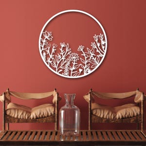 May include: White metal wall decor featuring a circular frame with a cutout design of stylized flowers and leaves.
