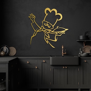 May include: A gold-colored metal wall art piece depicting a stylized chef wearing a tall toque hat and a neckerchief. The chef is shown in a dynamic pose with one hand raised and the other holding a serving platter, featuring clean, sharp lines.