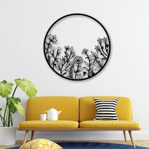 May include: Black metal wall decor featuring a circular design with a floral pattern. The design is reminiscent of a garden with various flowers and leaves.