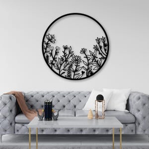 May include: Black metal wall decor featuring a circular design with a floral pattern. The design is reminiscent of a garden with various flowers and leaves.