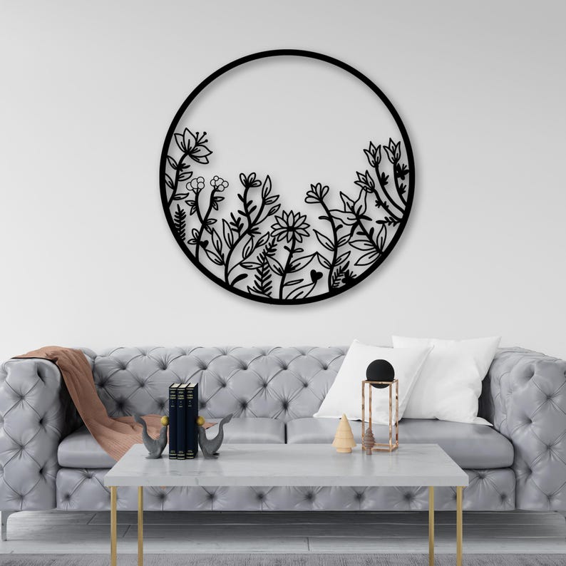 May include: Black metal wall decor featuring a circular design with a floral pattern. The design is reminiscent of a garden with various flowers and leaves.