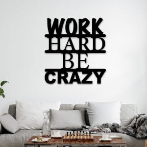May include: Black metal wall decor with the words "Work Hard Be Crazy" in a modern font.