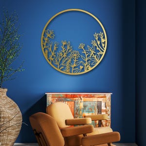 May include: Gold metal wall decor featuring a circular design with a floral pattern. The design is cut out of the metal, creating a delicate and intricate look.