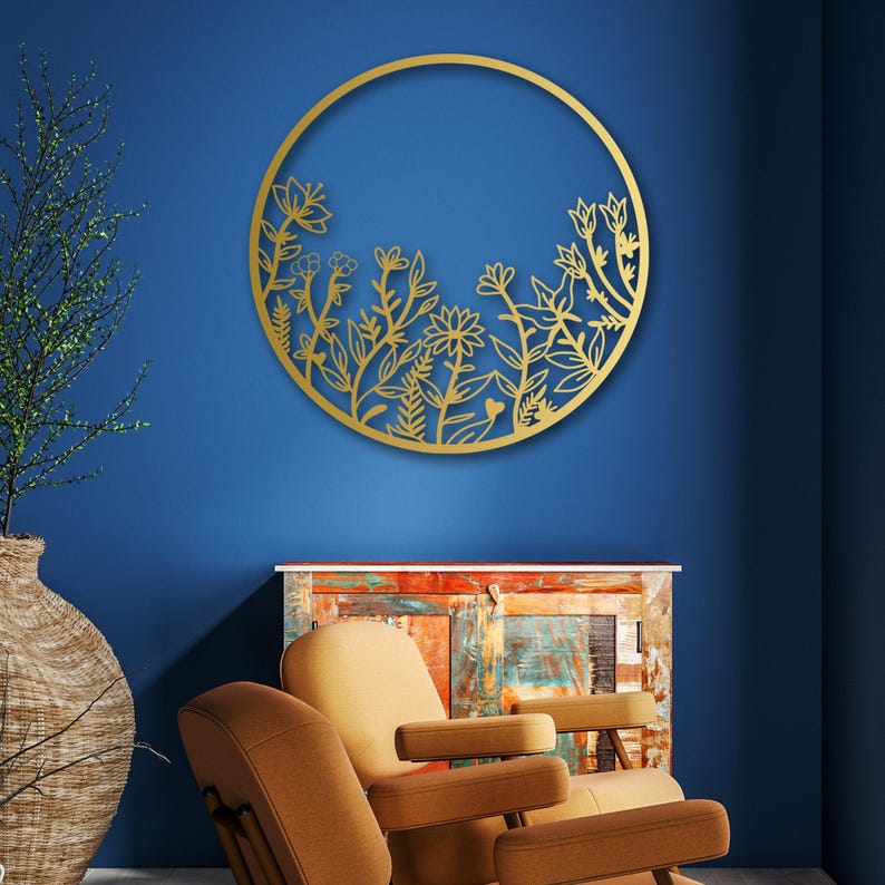 May include: Gold metal wall decor featuring a circular design with a floral pattern. The design is cut out of the metal, creating a delicate and intricate look.