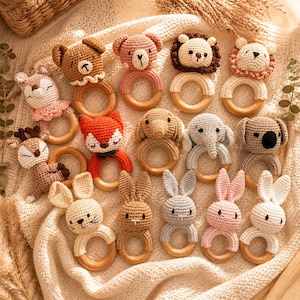 May include: A collection of crochet baby rattles in various animal designs, including a bear, lion, fox, elephant, and bunny. Each rattle features a wooden ring and is crafted in soft, neutral colors, perfect for a baby's sensory development.