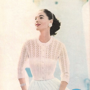 May include: A vintage knitting pattern for a white crocheted cardigan with a button-up front. The pattern is from Pattern Treasures.