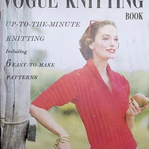 Może przedstawiać: Okładka zabytkowego magazynu Vogue Knitting Book z tytułem, podtytułem Up-To-The-Minute Knitting Including 6 Easy-To-Make Patterns oraz osobą w czerwonym swetrze w prążki z szalowym kołnierzem, trzymającą w dłoni gruszkę.