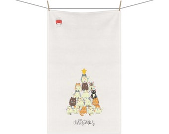 May include: White kitchen towel with a Christmas tree design made of cats. The cats are wearing Christmas lights and a star is on top of the tree. The text "Merry Christmas" is written below the tree.