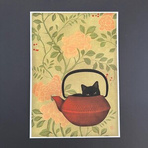 May include: A black cat sits inside a red teapot with a floral pattern background.
