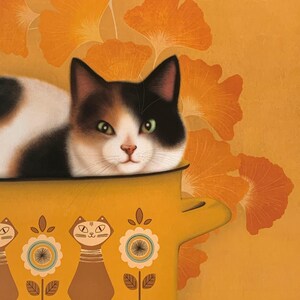 May include: A calico cat with green eyes peeks out of a yellow pot with a floral design. The pot has three stylized cats on the front.
