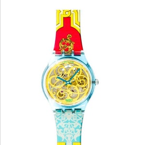 Könnte beinhalten: Eine Armbanduhr mit blau-gelbem Muster und einem goldenen Skelettzifferblatt. Die Uhr hat ein transparentes Kunststoffgehäuse und ein rot-gelb gemustertes Armband.
