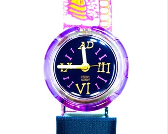 May include: A purple Swatch POP watch with a black face and gold Roman numeral hour markers. The watch has a pink and yellow patterned strap.