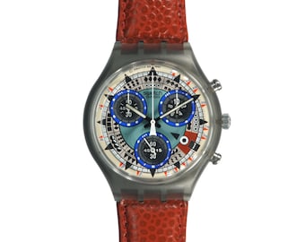 May include: A silver Swatch chronograph watch with a red leather band. The watch face has a white background with black and blue accents. The watch face features a chronograph with three subdials.