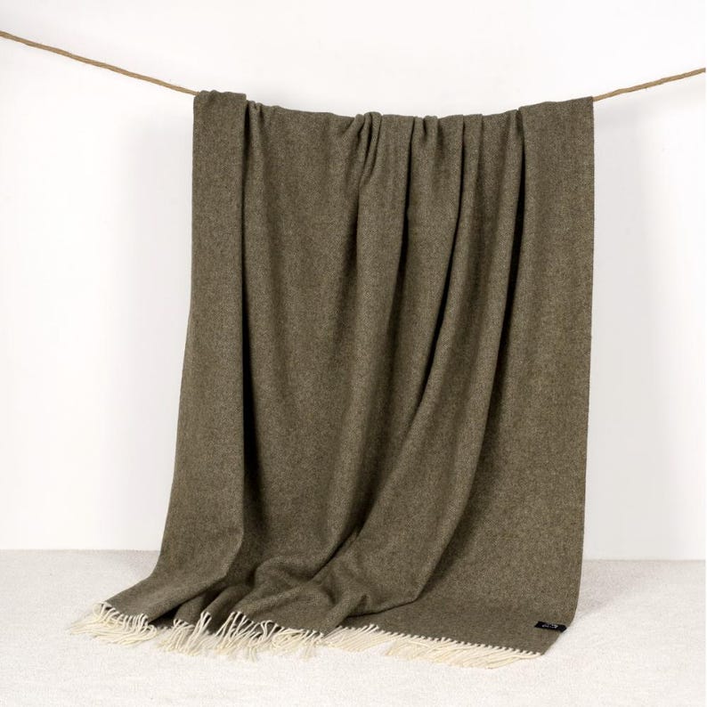Olive Green wool blanket is hanging over the metal bar