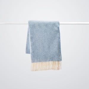 Luxury cashmere wool blanket in Sky Blue colour hanging.  Large 100% wool sofa throw very light but super warm