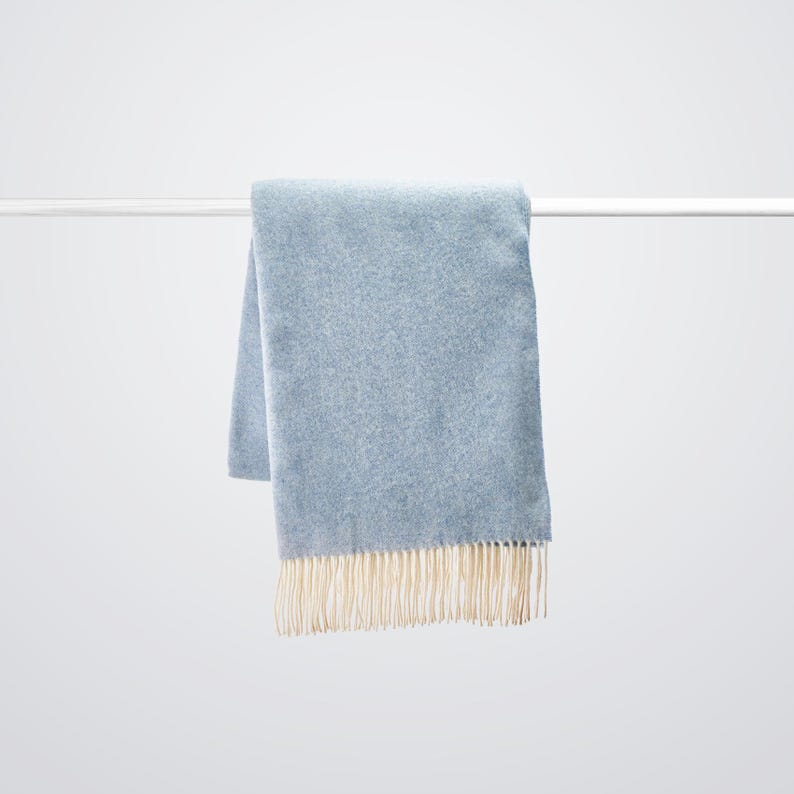 Luxury cashmere wool blanket in Sky Blue colour hanging.  Large 100% wool sofa throw very light but super warm