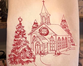 Puede incluir: Una toalla de tela color crema con un diseño bordado en hilo rojo de una iglesia con campanario, una corona en la fachada y un árbol de Navidad decorado a la izquierda, todo sobre un paisaje nevado.