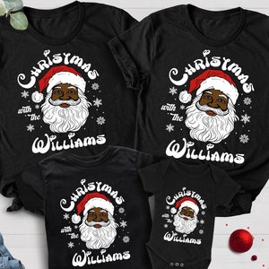 Peut inclure: Un ensemble de quatre t-shirts noirs sur le thème de Noël. Les t-shirts présentent une image de dessin animé d'un Père Noël noir avec le texte "Noël avec les Williams". Les t-shirts sont disponibles en tailles adultes et enfants.