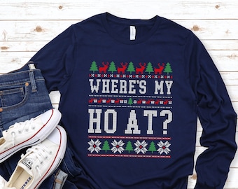 May include: A navy blue long-sleeved shirt with a Christmas-themed design. The shirt features a white, red, and green pattern with reindeer, snowflakes, and the text "Where's my Ho At?"