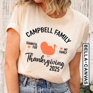 Puede incluir: Una camiseta blanca con texto negro que dice "Campbell Family Thankful For My Family Thanksgiving 2025". Un pavo naranja estilizado se encuentra entre las palabras "For" y "My".