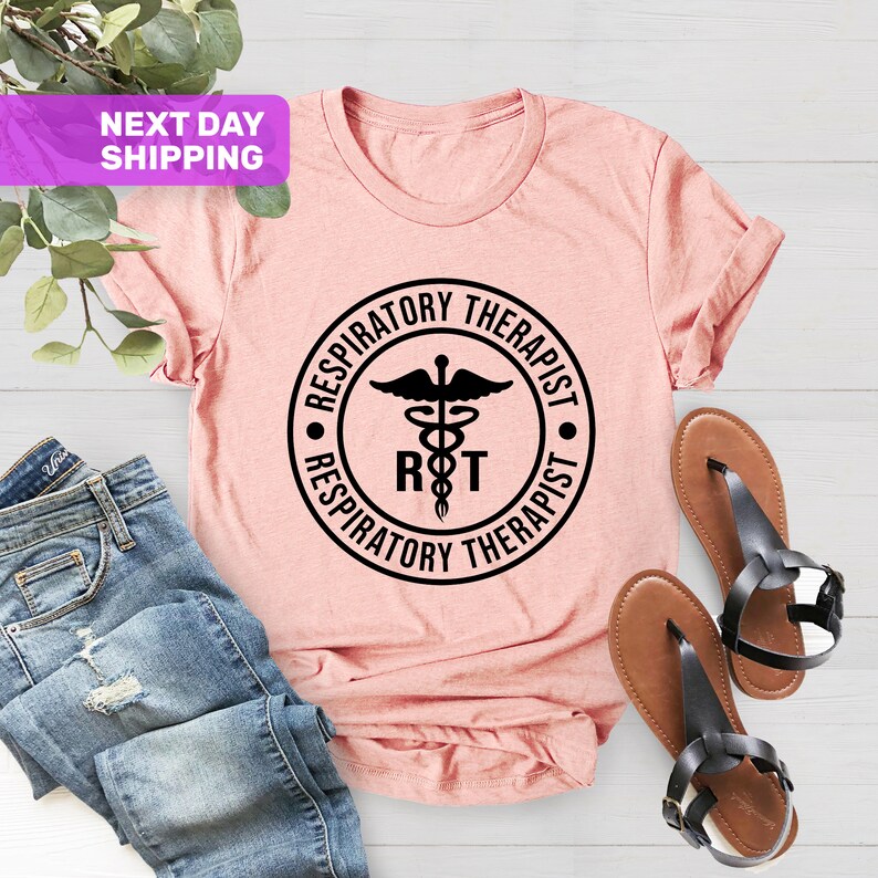 May include: A pink t-shirt with a black circle graphic that says "Respiratory Therapist" with a medical symbol and the letters "RT" inside the circle.