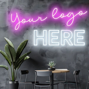 May include: A neon sign with the words "Your logo HERE" in pink and white against a dark gray wall. A potted plant and a small table with chairs are in the foreground, creating a modern interior design.