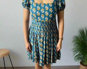May include: A teal knee-length dress featuring a square neckline, short puff sleeves, and a pleated waistline. The fabric is decorated with a repeating pattern of small yellow flowers with white stems and leaves, creating a consistent floral motif.