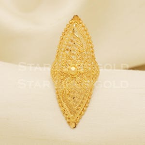 Puede incluir: Un anillo de oro con un diseño delicado e intrincado. El anillo tiene forma de lágrima y presenta un motivo floral en el centro.