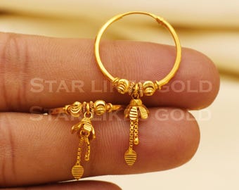 May include: A pair of gold-colored hoop earrings with a floral design and dangling chain accents. The earrings have a small, detailed flower shape with a chain and a teardrop-shaped charm. The text "STAR LIKE GOLD" is visible.