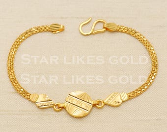 May include: A gold bracelet with a chain design and three decorative charms. The charms are round, heart-shaped, and a smaller round shape. The bracelet has a hook clasp.
