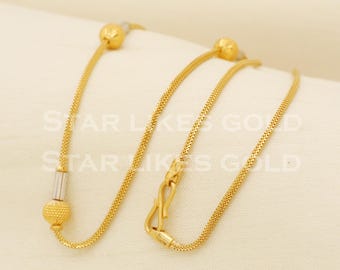 May include: A gold chain necklace with a delicate design and three small round charms. The chain is made of a fine, woven metal and has a secure clasp.