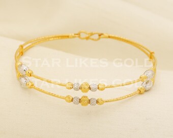 Puede incluir: Un brazalete de oro de doble hilo con alambre de oro amarillo texturizado y cuentas esféricas alternas en tono plateado y dorado. El texto STAR LIKES GOLD está superpuesto en el centro de la pieza de joyería.