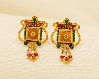 Può includere: Un paio di orecchini color oro con un design quadrato e multicolore. Gli orecchini presentano accenti rossi, verdi e oro, con una catena pendente di perline dorate e forme floreali rosse e oro nella parte inferiore.