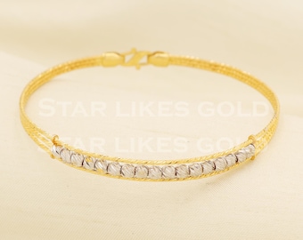 Könnte beinhalten: Ein goldenes Armband mit einer zentralen Reihe aus texturierten silberfarbenen Perlen, die von zwei dünnen Goldketten flankiert werden. Das Schmuckstück hat einen goldenen Karabinerverschluss und zeigt den Text STAR LIKES GOLD.