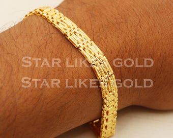 May include: A gold chain bracelet with a textured design. The bracelet is worn on a person's wrist.