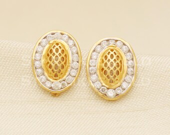 May include: A pair of gold oval earrings featuring a delicate, openwork design and a halo of sparkling white stones.